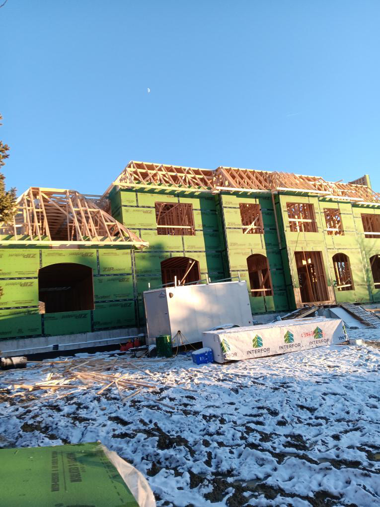 Large two-storey house with sheathed walls and exposed roof framing
